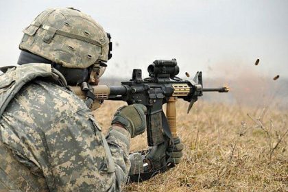 A soldier aiming through the scope mounted on his M4 Carbine