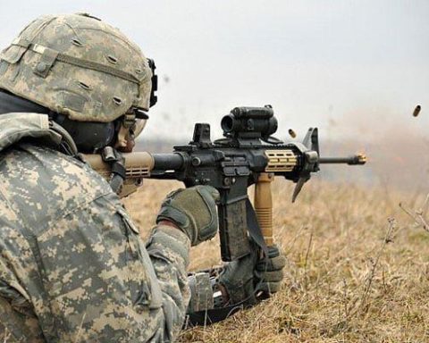 A soldier aiming through the scope mounted on his M4 Carbine