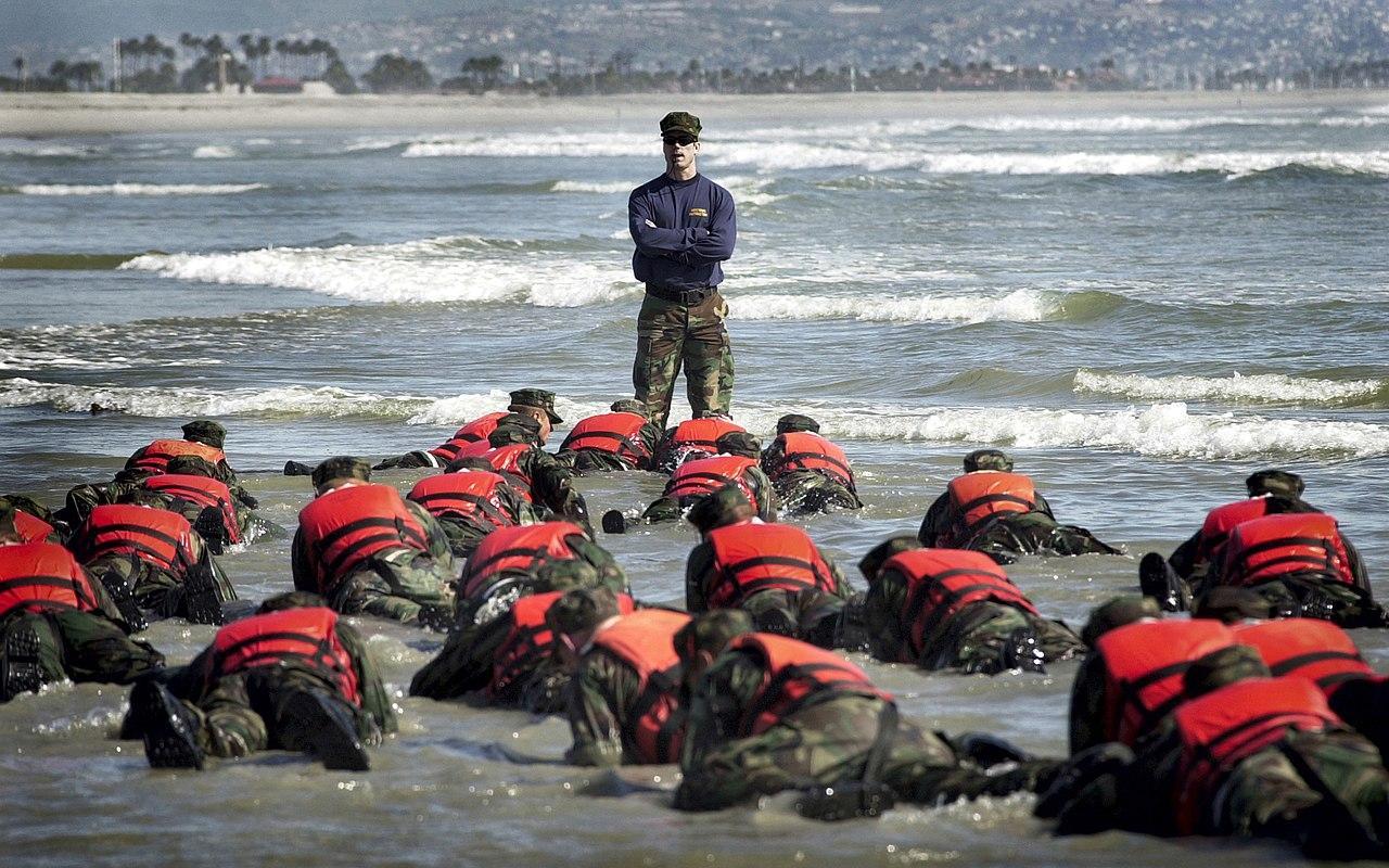 During a Hell Week surf drill evolution, a Navy SEAL instructor assists students from Basic Underwater Demolition/SEAL (BUD/S) class 245 with learning the importance of listening. 