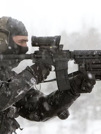 Special operations forces operator aiming through reflex sight on Colt Canada C7 rifle