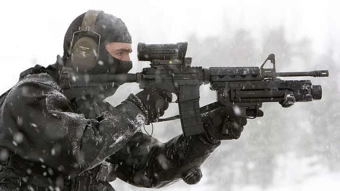 Special operations forces operator aiming through reflex sight on Colt Canada C7 rifle