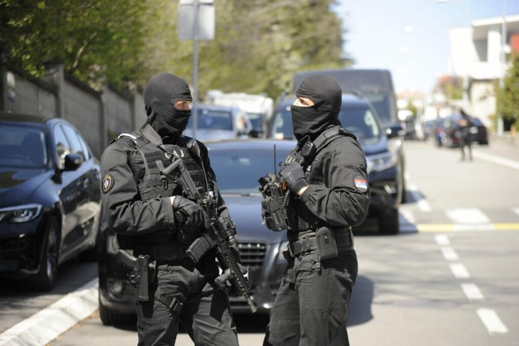 Two SAJ operators in uniform standing on the street in front of a black vehicle