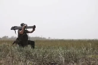 Soldier holding an RPG-30 shoulder-fired rocket launcher in a field